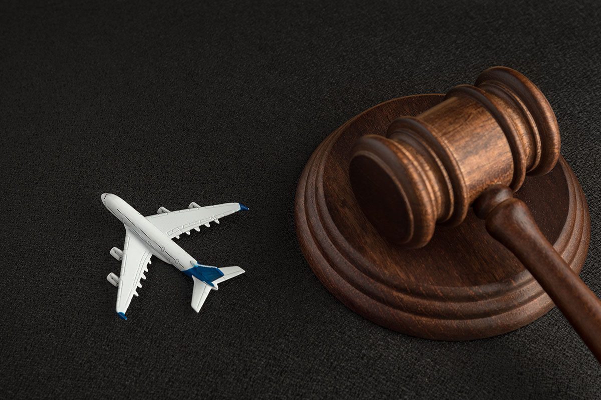 A wooden judge’s gavel next to a small model airplane on a dark surface.