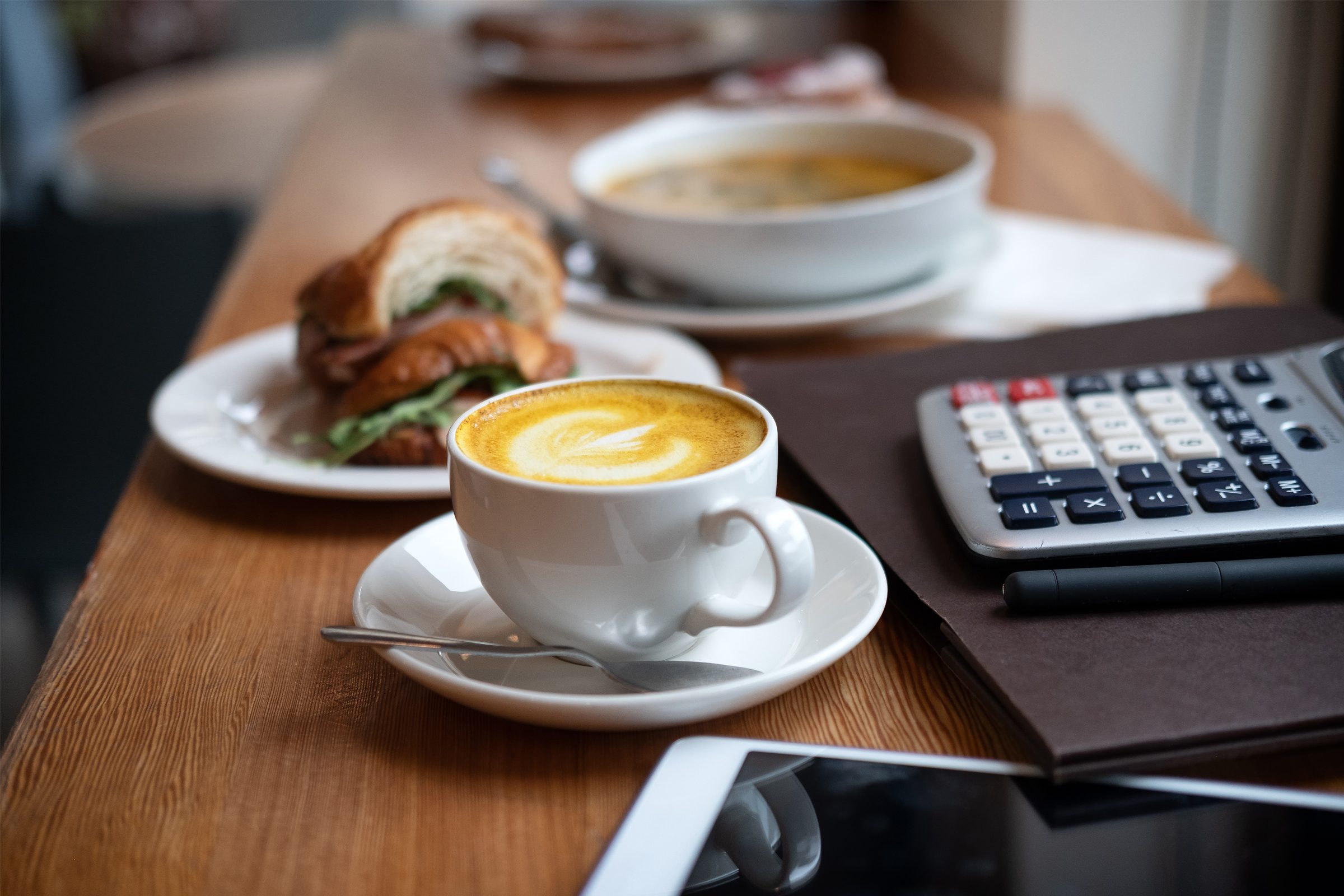 A cup of coffee with latte art sits on a saucer with a spoon